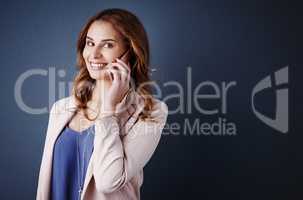 Connecting with my best client. Studio portrait of an attractive young businesswoman using a mobile phone against a dark blue background.