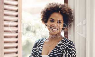Beautiful, happy and edgy african woman smiling and showing a positive attitude while standing alone. Portrait of attractive black female with curly afro and friendly attitude while relaxing at home