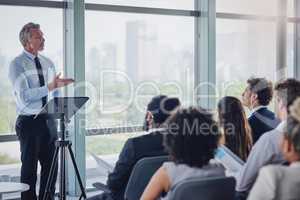 Hes got a wealth of experience to share. High angle shot of a handsome mature male speaker addressing a group of businesspeople during a seminar in the conference room.