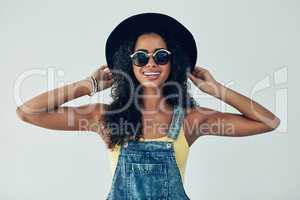 Having fun with my funky hat. Studio shot of an attractive young woman posing against a grey background.