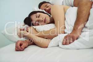 When youre comfortable as ever. a relaxed young couple sleeping in each others arms in bed during morning hours.