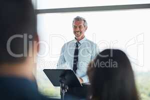 Talking with poise and purpose. a handsome mature businessman speaking at a business conference.