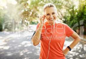Fit female athlete going for morning run, adjusting earphones, listening to music. Happy, healthy sports woman smiling, about to do cardio wellness exercise or take endurance training workout break.