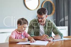 Dads there to give him all the guidance he needs. a father helping his little son with his homework.