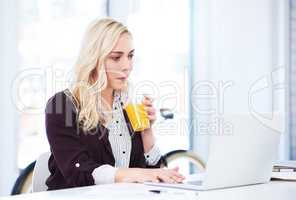Business wont get in the way of her cleanse. an attractive young businesswoman drinking orange juice while working in her office.