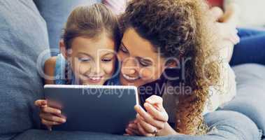 Entertainment sorted for their mommy daughter bonding session. a cute little girl using a digital tablet with her mother on the sofa at home.