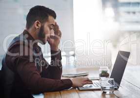 I just need to get through the day. a young businessman looking stressed out while working in an office.