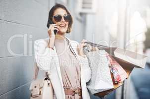 Carefree and excited shopping woman on a phone call holding bags outdoors in the city. Stylish, trendy and wealthy female enjoying her weekend while on vacation or holiday in an urban town