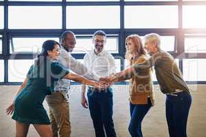 Teamwork, fun and collaboration by diverse team joining hands in team building. Excited group linking, joining and supporting goal, mission or vision at work. Trust by professional creative coworkers