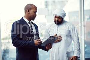 Growing a business is a team task. two businessmen using a digital tablet while having a discussion in a modern office.