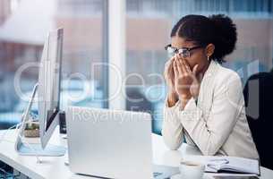 From ambitious to burned out. a young businesswoman looking stressed at her desk in a modern office.