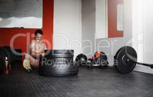 His goal is within reach. Full length shot of a handsome and muscular young man pulling weights in the gym.