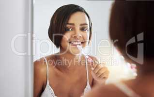 Got to keep them sparkly and white. Portrait of an attractive young woman brushing her teeth in the bathroom.