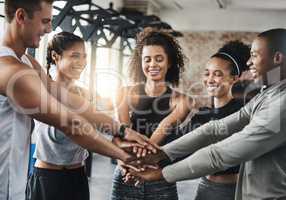 Gym fans unite. a group of young people joining their hands together in solidarity at a gym.