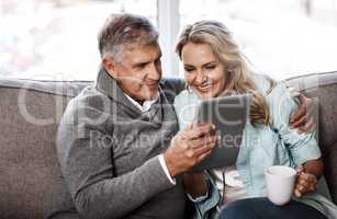 The world online never fails to intrigue. a mature couple using a digital tablet together at home.
