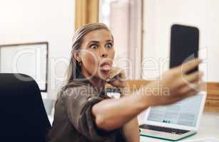 Phone selfie with a playful business woman having fun, being goofy and joking while working in her office. Young female sticking out her tongue and making a face at work while feeling carefree