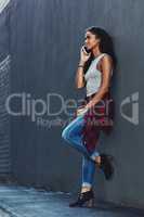 Calling friends to join me in the city. an attractive young woman on a call posing against a wall in the city.