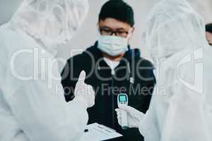 Negative covid test and thumbs up for young man from healthcare worker after testing for virus. Medical professionals in hazmat suits taking temperature tests during disease outbreak or pandemic
