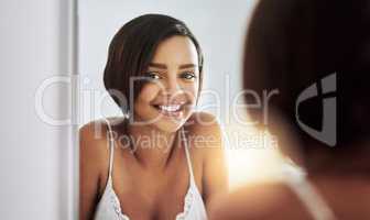 Keeping up with her beauty regime. Portrait of an attractive young woman looking at her face in the bathroom mirror.