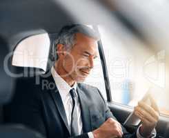 Staying connected on the move. a handsome mature businessman using a tablet while sitting in the backseat of a car during his morning commute.