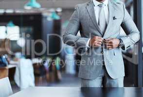 Confidence forms part of how you attire yourself as well. Closeup shot of an unrecognizable businessman fastening the button on his suit in an office.