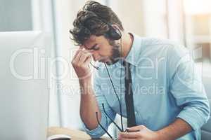 Some calls are more stressful than others. a young man experiencing stress while working in a call center.