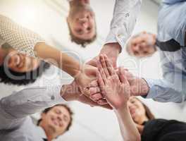 Success is the hands of a team. Low angle shot of a group of colleagues joining hands in solidarity in a modern office.