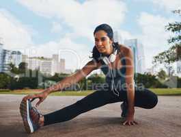 You gotta stretch to get the blood flowing. Full length shot of an attractive young sportswoman doing stretch exercises outdoors in the city.