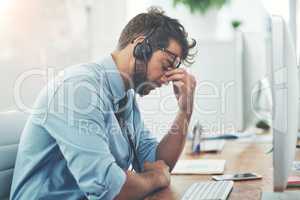 Trying to reach his sales target is stressing him out. a young man experiencing stress while working in a call center.