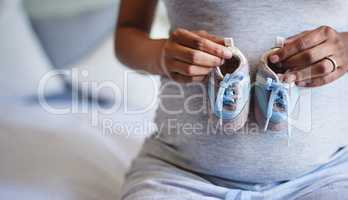 Tiny blue shoes for my tiny little bub. a pregnant woman holding a pair of blue baby shoes in front of her belly.