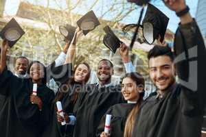 Were proof that hard work does pay off. Portrait of a group of happy young students taking their hats off on graduation day.