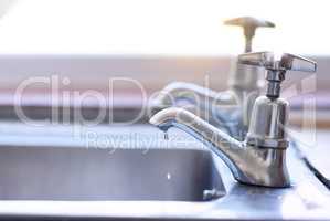 Close all of your taps after using. two dripping taps waisting a little bit of water in a basin inside of a house during the day.