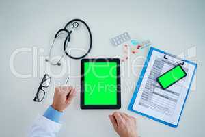 Technology helps make significant contributions to the improvement of healthcare. High angle shot of an unrecognizable doctor using a digital tablet and cellphone with a green screen in his office.