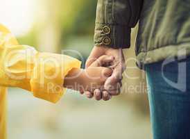 Its raining, you might need an adult to accompany you. Closeup shot of an unrecognizable little boy and his mother holding hands in the rain outside.