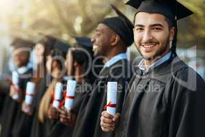 Proud does not begin to describe the feeling. Portrait of a young man holding his diploma while standing with his fellow students on graduation day.