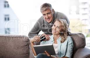 We have access to some of the best deals online. Portrait of a mature couple using a digital tablet and credit card to do online shopping at home.