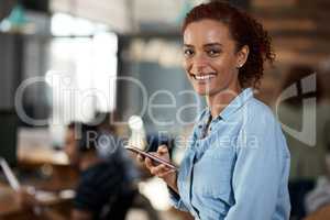 Loving the ease that these apps add to my workday. Portrait of an attractive young businesswoman using a cellphone in an office.