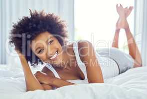 Its a lay in bed type of day for me. an attractive young woman chilling on her bed at home.