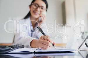 Checking her schedule. a young female doctor making notes while working in a hospital.