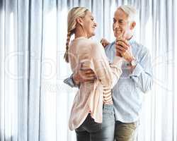 Right here is where we belong. an affectionate mature couple dancing in their home.