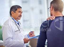 It is important that you take it easy from now on. a confident mature male doctor doing a checkup on a patient while standing inside of a hospital during the day.