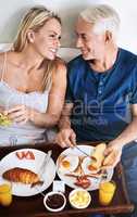 I cant imagine a better start to the day. an affectionate mature couple enjoying breakfast in bed at home.