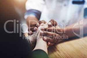 Interracial couple holding hands in support, comfort and trust while bonding and feeling united in home living room. Closeup of man touching, comforting or caring for woman who has anxiety in therapy