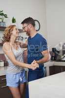 Dance to the tune of love. a happy middle aged couple dancing in the kitchen at home.