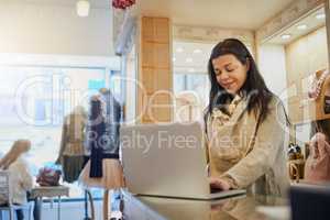 Using online resources to manage her business. an attractive mature female entrepreneur working on a laptop in her self-owned boutique.