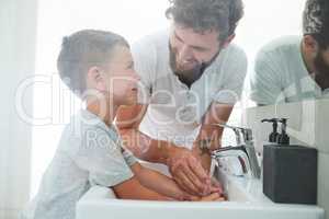 Cleanliness is important, so always wash your hands. a young handsome father helping his adorable little boy wash his hands in the bathroom at home.