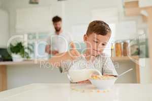 Fuel for a busy day of play. an adorable little boy having breakfast with his father in the background at home.