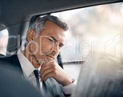 This makes for some interesting reading. a handsome mature businessman reading the paper while sitting in the backseat of a car during his morning commute.