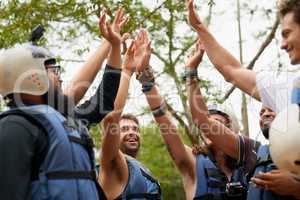 This is for being an adventurer seeker. a group of young male friends giving each other a high five before they go white water rafting.