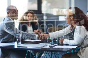 Its a good deal for all parties concerned. two young businesspeople shaking hands during a meeting in the boardroom.